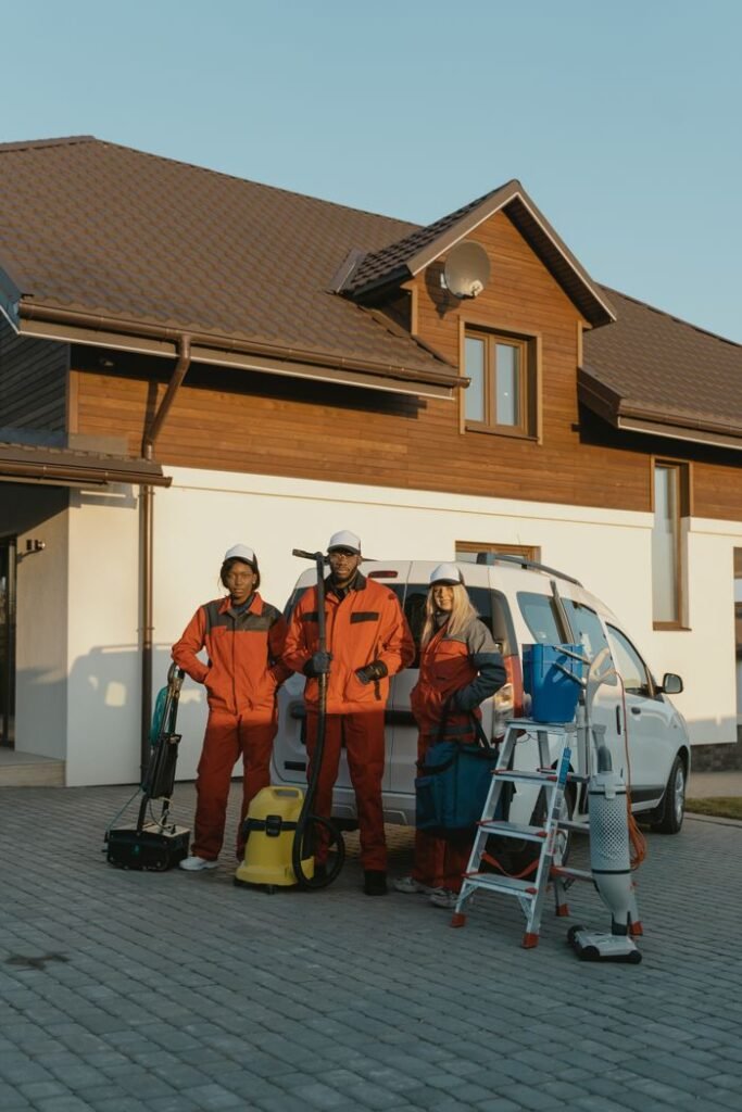 Cleaning crew in uniforms with equipment standing outside a modern house.